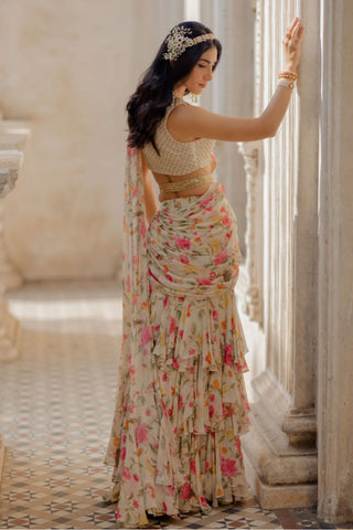 Model showing the blouse from the back. A maharani kangri blouse which is hand embroidered with cutdana and tone to tone thread. It has a covered back and is crafted from soft malai chanderi. The off white three layered pre–draped chintz and bird printed saree. Super easy to wear. Perfect for wedding parties, engagement celebration, mehndi ceremonies or festivities.