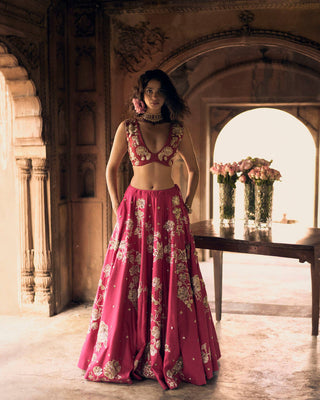 A rani pink lehenga featuring different motif placement on each kali, lending a modern romantic charm. The lehenga and blouse feature intricate hand–embroidery in zardozi, aari and sequins and are complemented with an ombré dupatta.