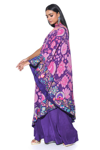 Violet Siddharth Bansal Signature Royal Paisley Print And Heavy Hand Embroidered Border One Shoulder Cape Dress Paired With Tangy Purple Inverted Box Pleat, Wide Leg Jumpsuit.